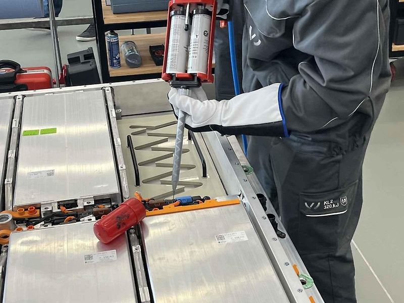 Vyjmutá baterie z vozu, ležící na hydraulickém stole a propojená s vozem prodlužovacími kabely