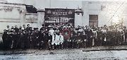 Společná fotografie zaměstnanců Walterova podniku u továrny Na Zatlance v roce 1912, Josef Walter sedí uprostřed v buřince