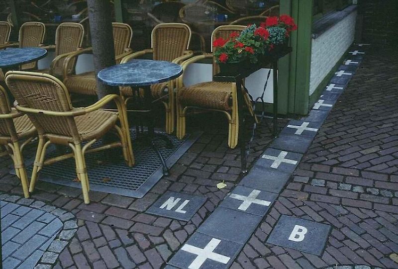 Dům ve dvou státech. Státní hranice je vyznačena bílými křížky na chodníku.