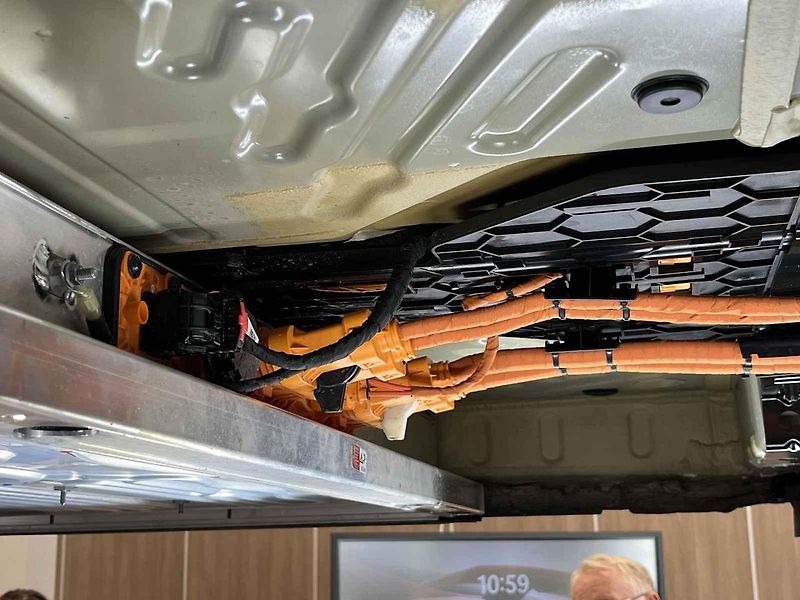 Vyjmutá baterie z vozu, ležící na hydraulickém stole a propojená s vozem prodlužovacími kabely