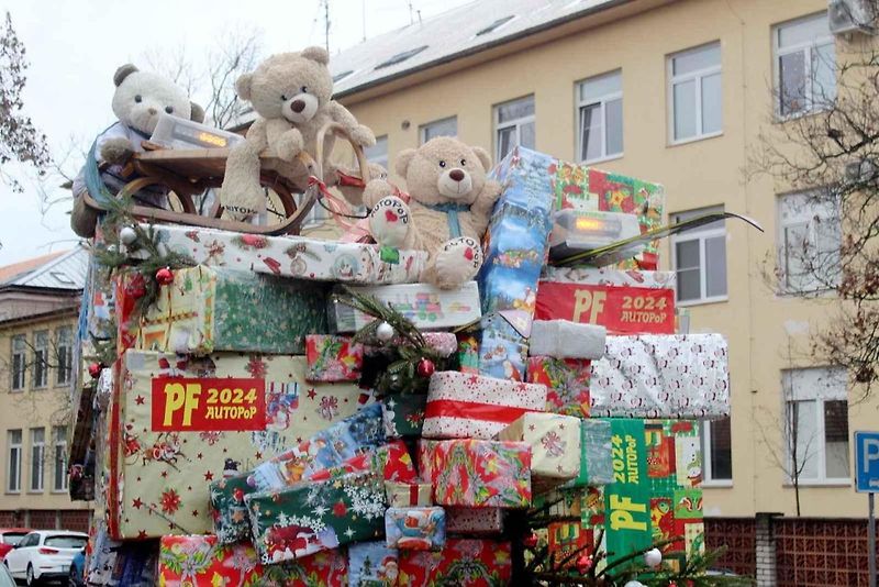 Auto se spoustou dárků na střeše budí rozruch vedle kruhového objezdu u nemocnice.