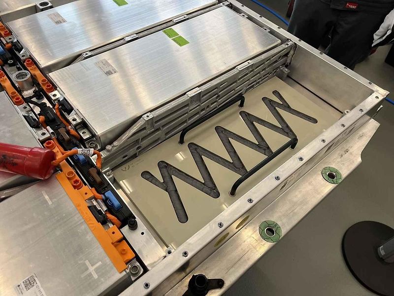 Vyjmutá baterie z vozu, ležící na hydraulickém stole a propojená s vozem prodlužovacími kabely