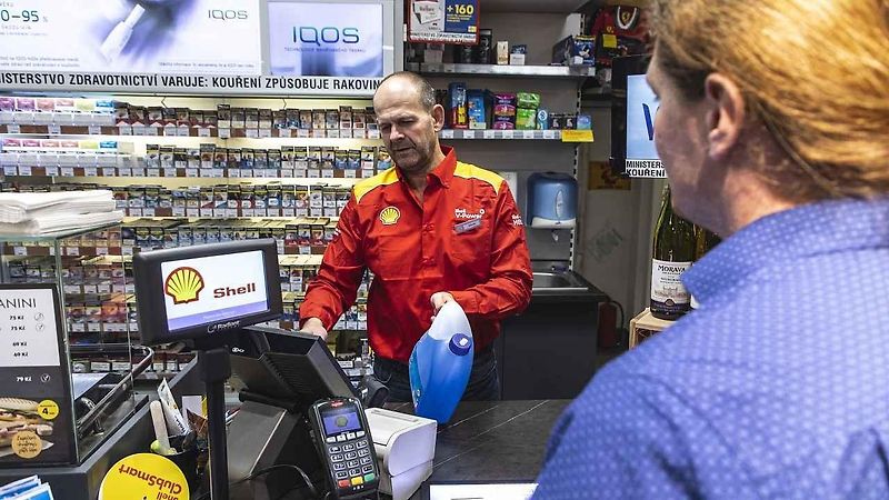 Venkovní prodejce pomáhá lidem s tankováním a současně je informuje o přednostech prémiovějších typů paliv