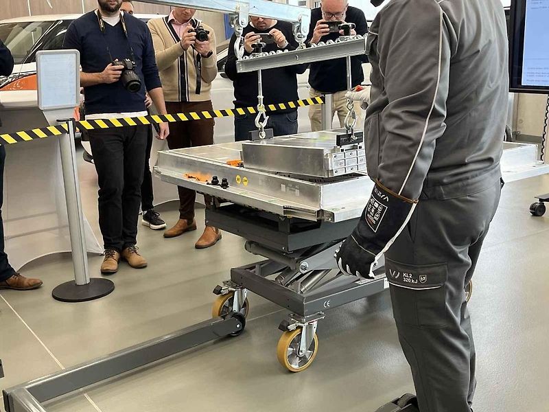 Vyjmutá baterie z vozu, ležící na hydraulickém stole a propojená s vozem prodlužovacími kabely