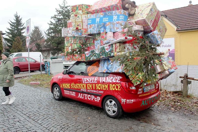 Auto se spoustou dárků na střeše budí rozruch vedle kruhového objezdu u nemocnice.