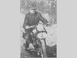 George Brough, jezdil motocyklové závody se speciální plochou čepicí.