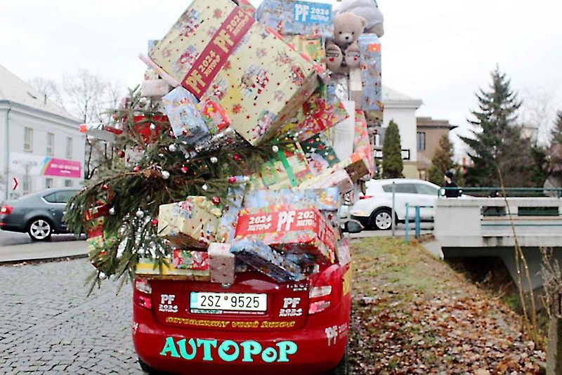 Auto se spoustou dárků na střeše budí rozruch vedle kruhového objezdu u nemocnice.