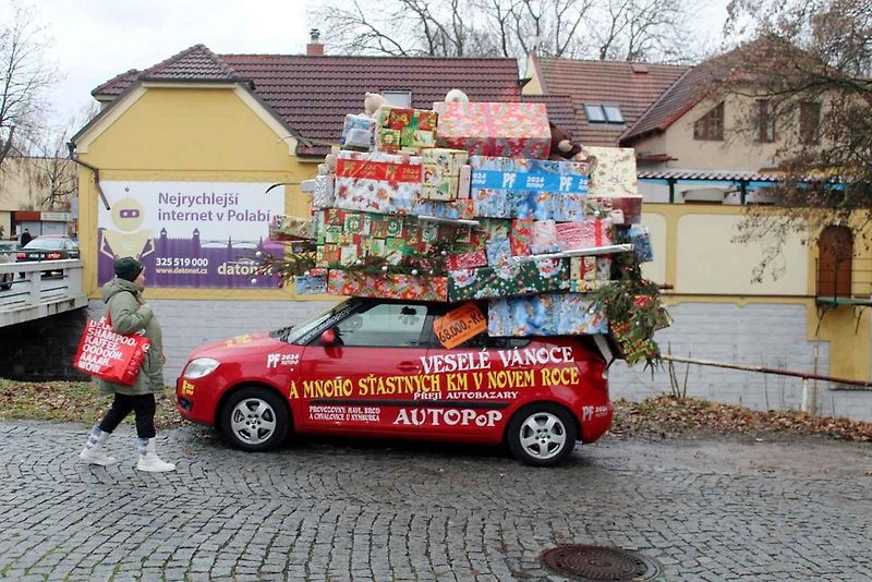 Auto se spoustou dárků na střeše budí rozruch vedle kruhového objezdu u nemocnice.
