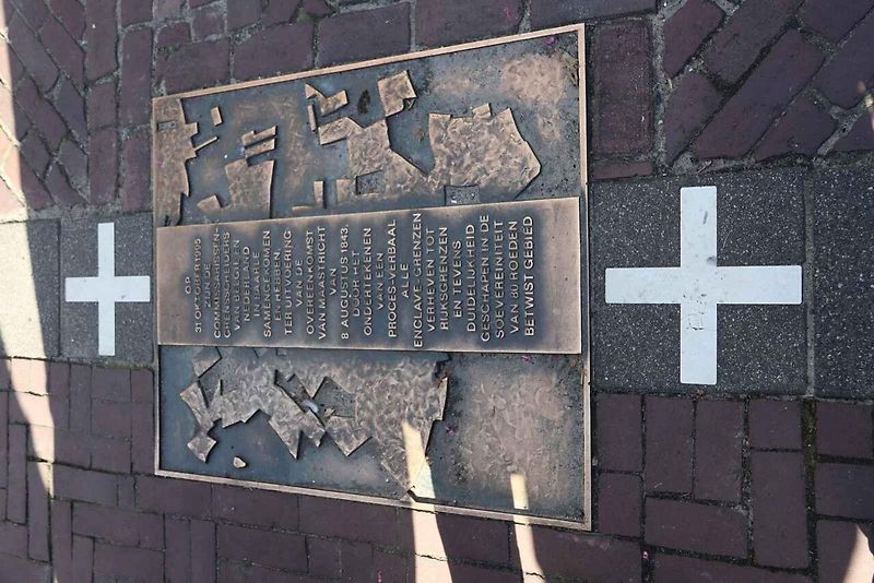 Dům ve dvou státech. Státní hranice je vyznačena bílými křížky na chodníku.