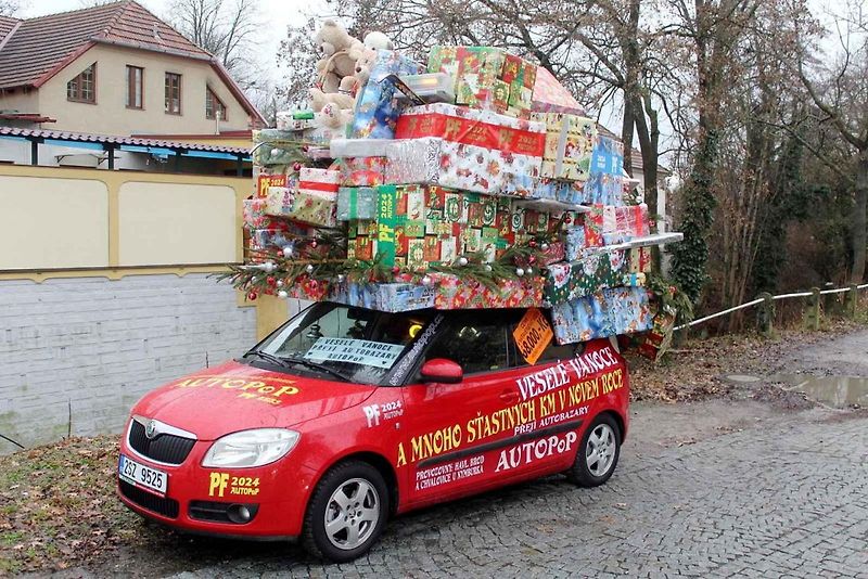 Auto se spoustou dárků na střeše budí rozruch vedle kruhového objezdu u nemocnice.