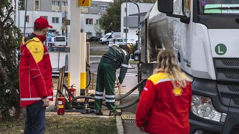 Venkovní prodejce pomáhá lidem s tankováním a současně je informuje o přednostech prémiovějších typů paliv