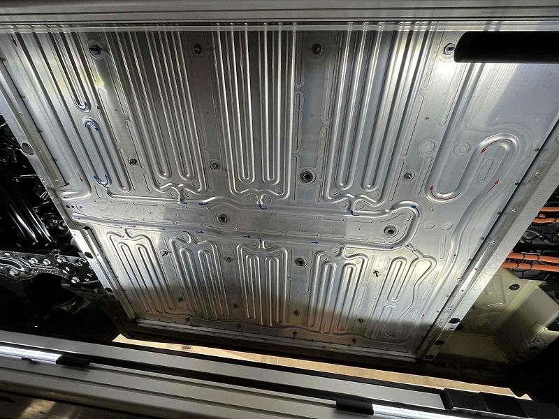 Vyjmutá baterie z vozu, ležící na hydraulickém stole a propojená s vozem prodlužovacími kabely