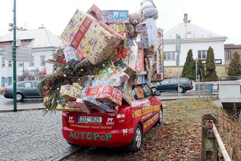 Auto se spoustou dárků na střeše budí rozruch vedle kruhového objezdu u nemocnice.