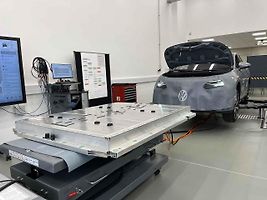 Vyjmutá baterie z vozu, ležící na hydraulickém stole a propojená s vozem prodlužovacími kabely